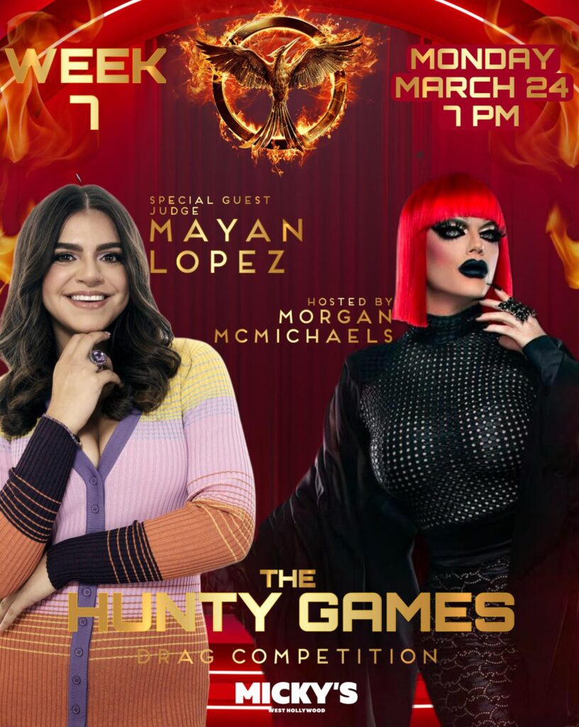 Promotional poster for 'The Hunty Games' drag competition at Micky’s West Hollywood, featuring host Morgan McMichaels in a striking fiery-red outfit with a dramatic background of flames and the iconic 'Hunger Games' emblem. Special guest judge Mayan Lopez is shown smiling, adding star appeal. Event details state the competition occurs on Monday, March 24 at 7 PM.